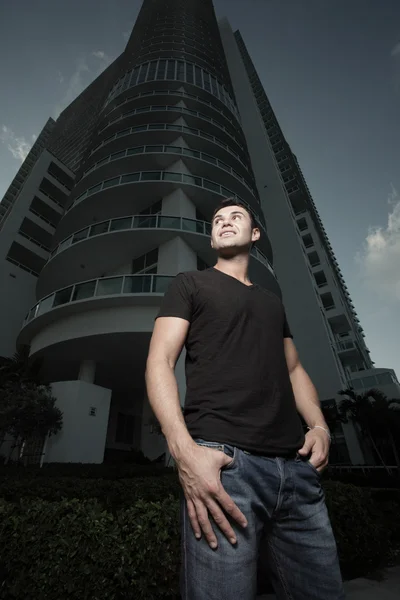Homem posando por um prédio alto à noite — Fotografia de Stock