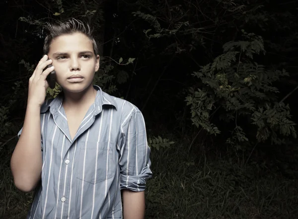Ung pojke talar i en mobiltelefon — Stockfoto