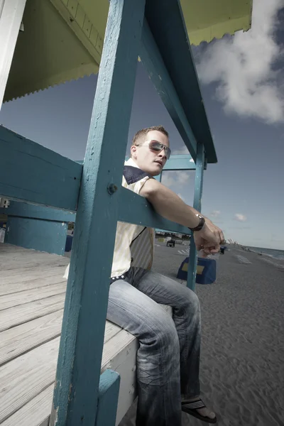 Homem sentado em uma cabana salva-vidas — Fotografia de Stock