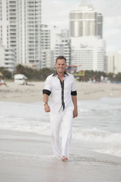 Mann geht am Strand spazieren und lächelt — Stockfoto