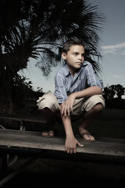 Boy squatting on a table — Stock Photo, Image
