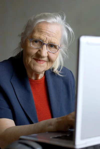 Літня жінка друкує на ноутбуці — стокове фото