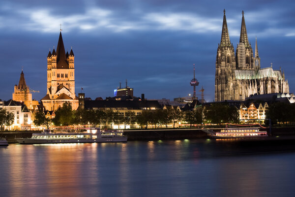 Dom and Great St. Martin church in Cologne at sunset lighting with reflection in river Rhine.