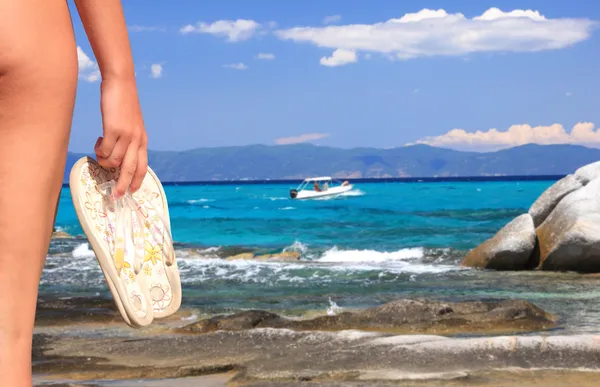 Kvinna med floppar på strandlinjen — Stockfoto