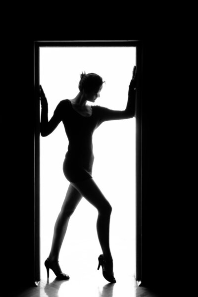 Outlines of a beautiful young woman standing by a door