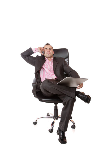 Relaxed young businessman, sitting on a chair with laptop. Isolated on white background.
