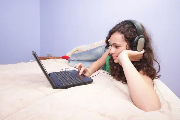 Chica adolescente en la cama mirando en su computadora portátil —  Fotos de Stock