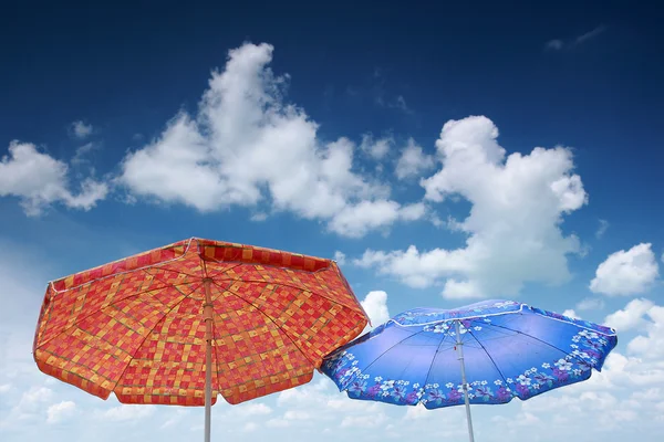 Дві пляжні парасольки і блакитне хмарне небо — стокове фото