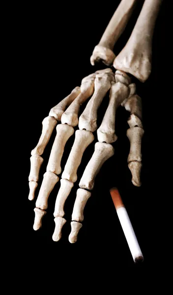 Esqueleto mano caer un cigarrillo — Foto de Stock