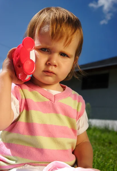 Criança pequena com telefone de brinquedo — Fotografia de Stock