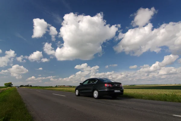 Дорога, автомобиль, голубое облачное небо — стоковое фото
