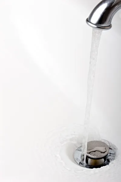 Acqua corrente del rubinetto in un lavandino da vicino Immagini Stock Royalty Free