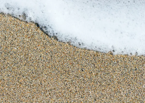 Meeresschaumwelle auf Sand aus nächster Nähe Stockbild