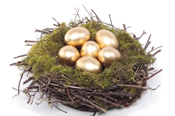 Golden eggs in bird nest over white — Stock Photo, Image