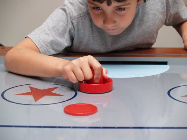 Young boy playing air hockey clipart