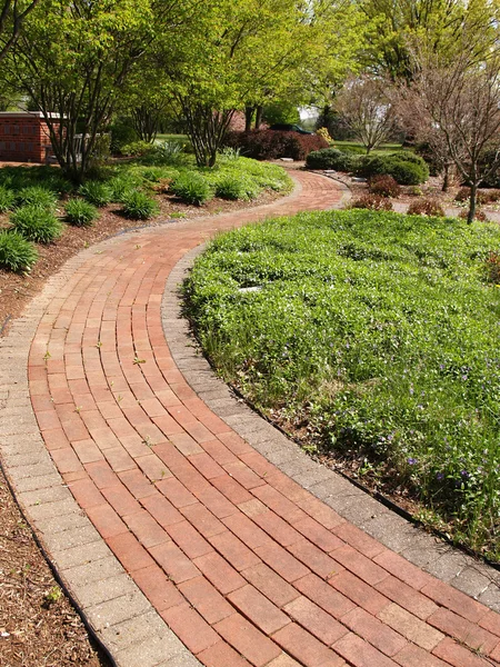 Kronkelende baksteen pad in een tuin — Stockfoto