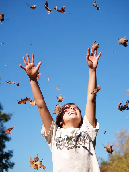 Junge wirft Blätter in die Luft — Stockfoto
