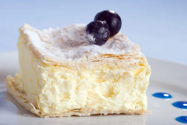 Kremalı kek kare ile blue bir tabakta — Stok fotoğraf