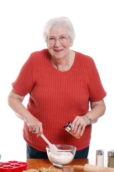 Ανώτερος γυναίκα προσθέτοντας μπαχαρικά για ψήσιμο — Φωτογραφία Αρχείου