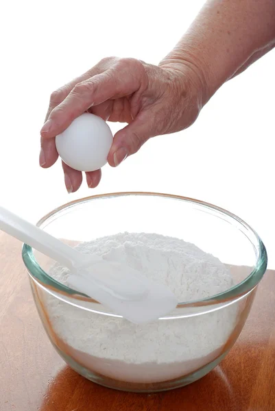 Oudere vrouw breken een ei in kom — Stockfoto