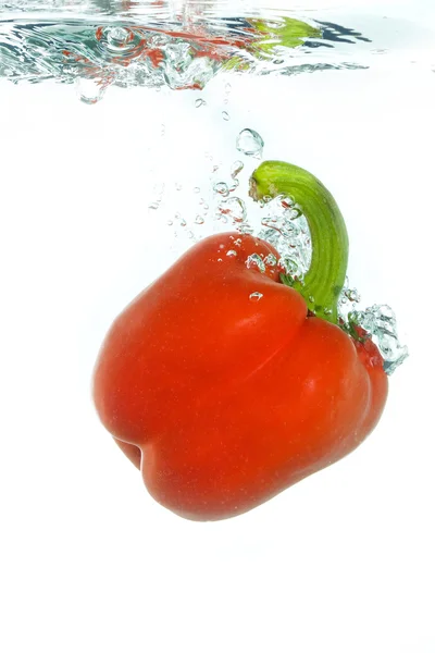 Un paprika tombant dans l'eau claire — Photo
