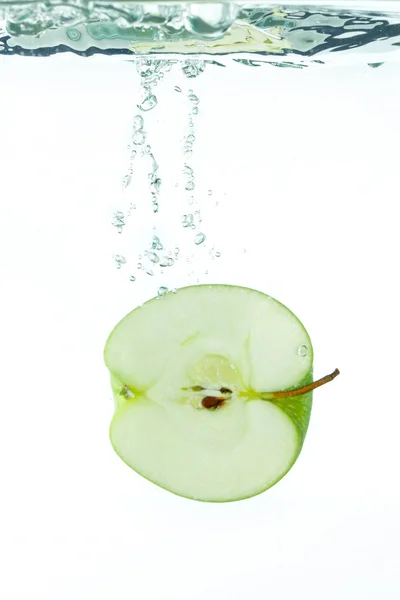 Ein in Scheiben geschnittener Apfel fällt ins Wasser — Stockfoto