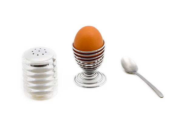 Un huevo en una taza de huevo junto a una lata de sal — Foto de Stock