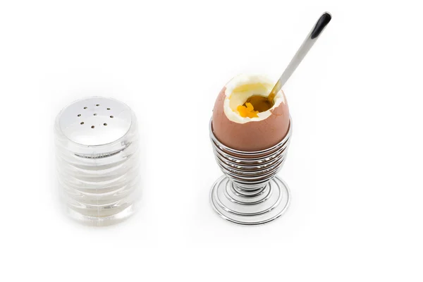 Un huevo en una taza de huevo junto a una lata de sal — Foto de Stock