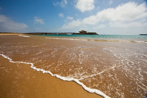 Une belle plage avec une jetée dans la mer — Photo