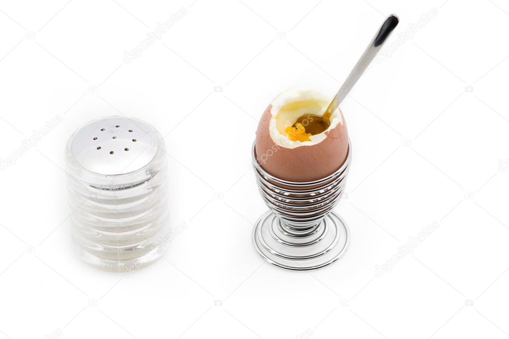 An egg on an eggcup next to a salt can