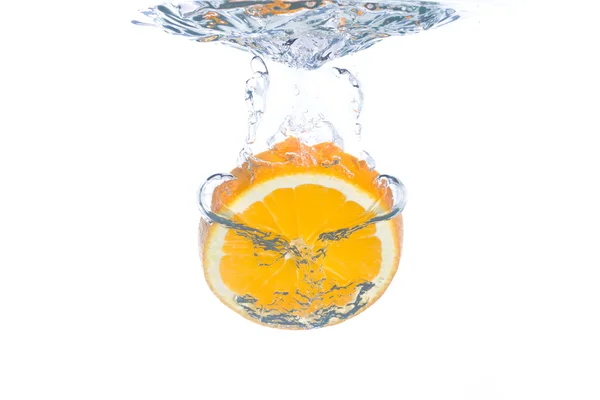 Uma fatia de laranja caindo em água limpa — Fotografia de Stock