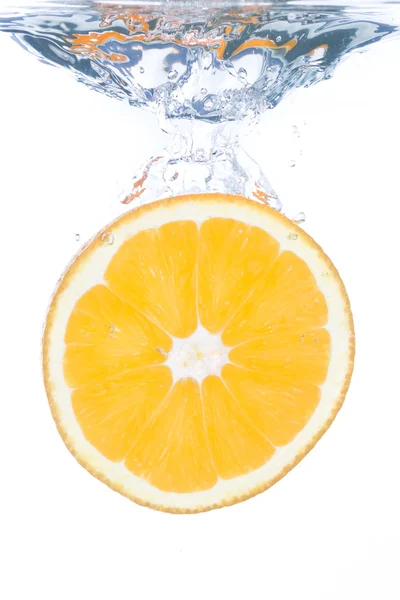 En orange skiva falla i klart vatten — Stockfoto