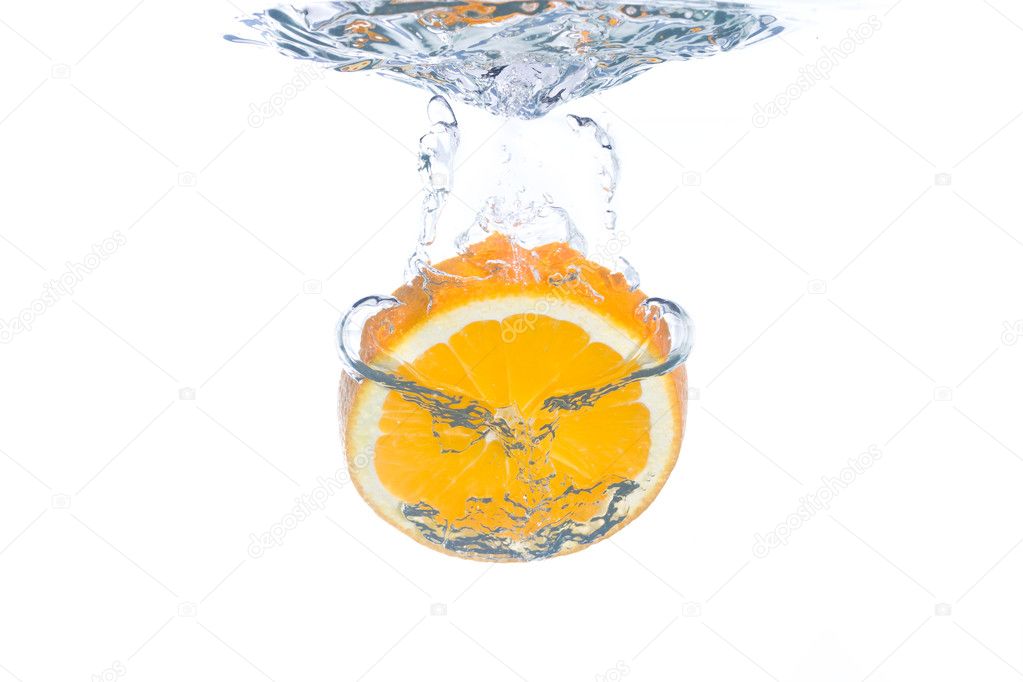 An orange slice falling into clear water