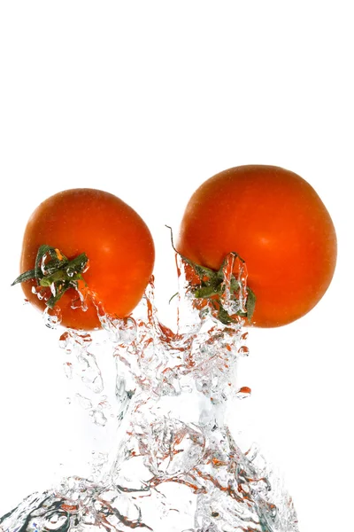 Zwei Tomaten springen aus dem klaren Wasser Stockbild