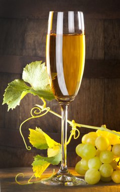 Glass of white wine with bunch of grapes clipart