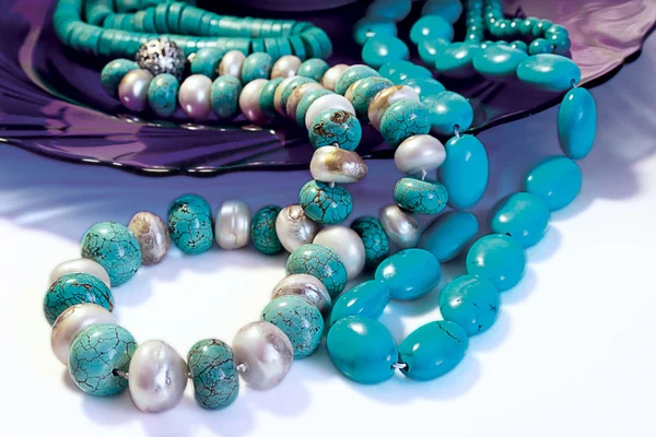 Turquoise beads on deep-blue glass plat Royalty Free Stock Images