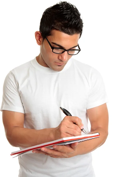 Student w okularach pisze w książce — Zdjęcie stockowe