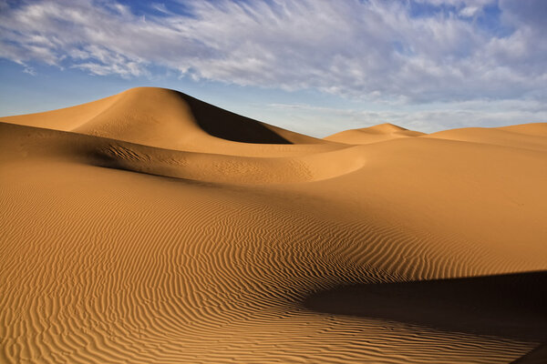 Пустынные песчаные дюны с облачным голубым небом

