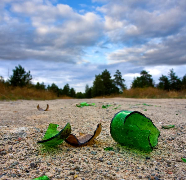 Разбитая стеклянная бутылка на дороге — стоковое фото