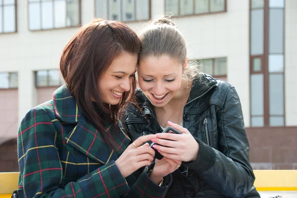 Молодые девушки смотрят что-то в мобиле — стоковое фото