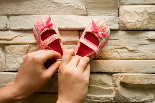 Petites chaussures de bébé roses sur mur en pierre Photos De Stock Libres De Droits