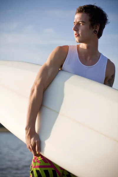 Человек на пляже с доской для серфинга — стоковое фото