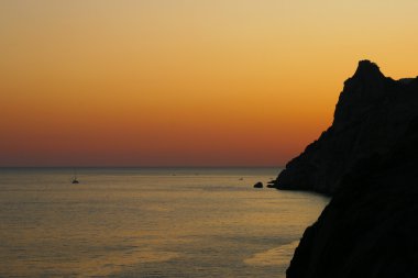 günbatımı üzerinde deniz ve kayalıklarla