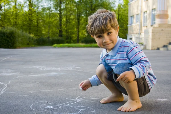 Chlapec kreslí s křídou na asfalt — Stock fotografie