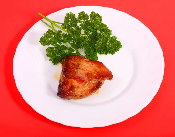 Pečené maso na talíři (červené pozadí) — Stock fotografie