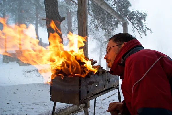 Άνθρωπος fanning πυρκαγιά στη σχάρα — Φωτογραφία Αρχείου