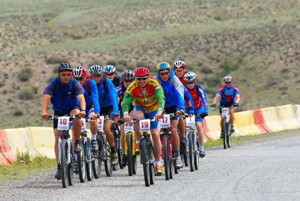 赛车在沙漠公路上的山骑自行车的人组 — 图库照片