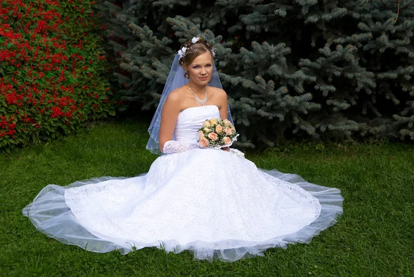 Loira noiva senta-se na grama — Fotografia de Stock