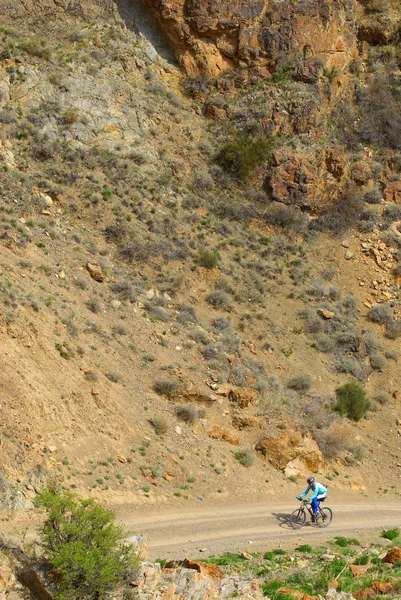 Rowerzysta na wiejskiej drodze w górach pustyni — Zdjęcie stockowe