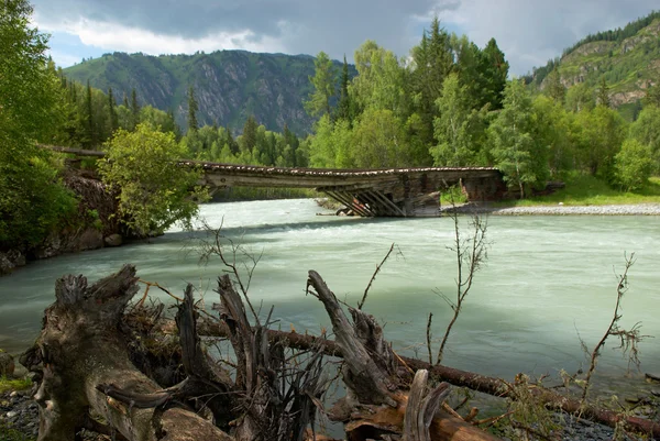 Gebirgsfluss und alte Holzbrücke — Stockfoto